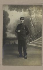[Photographie en pied d'un homme en uniforme militaire sur un fond de décor.]